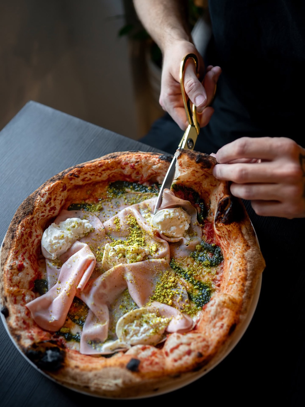 Pizza s mortadellou a burratou krájaná zlatými nožnicami